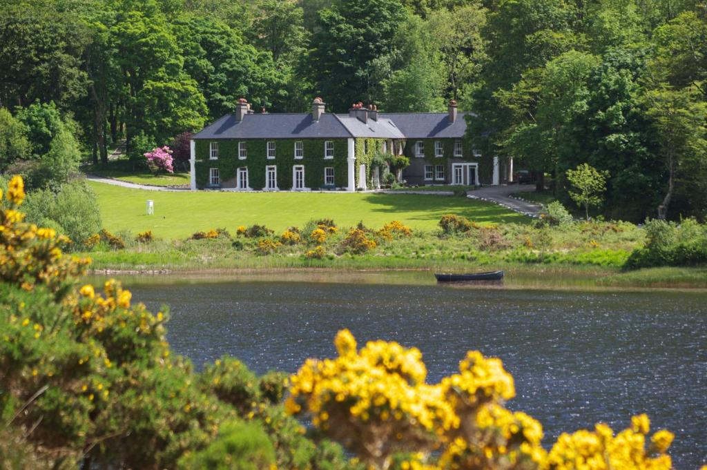 a large house with a lake in front of it at Delphi Lodge in Leenaun