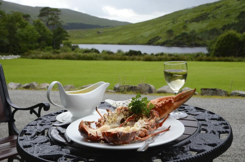 a table with a plate of food and a glass of wine at Delphi Lodge in Leenaun