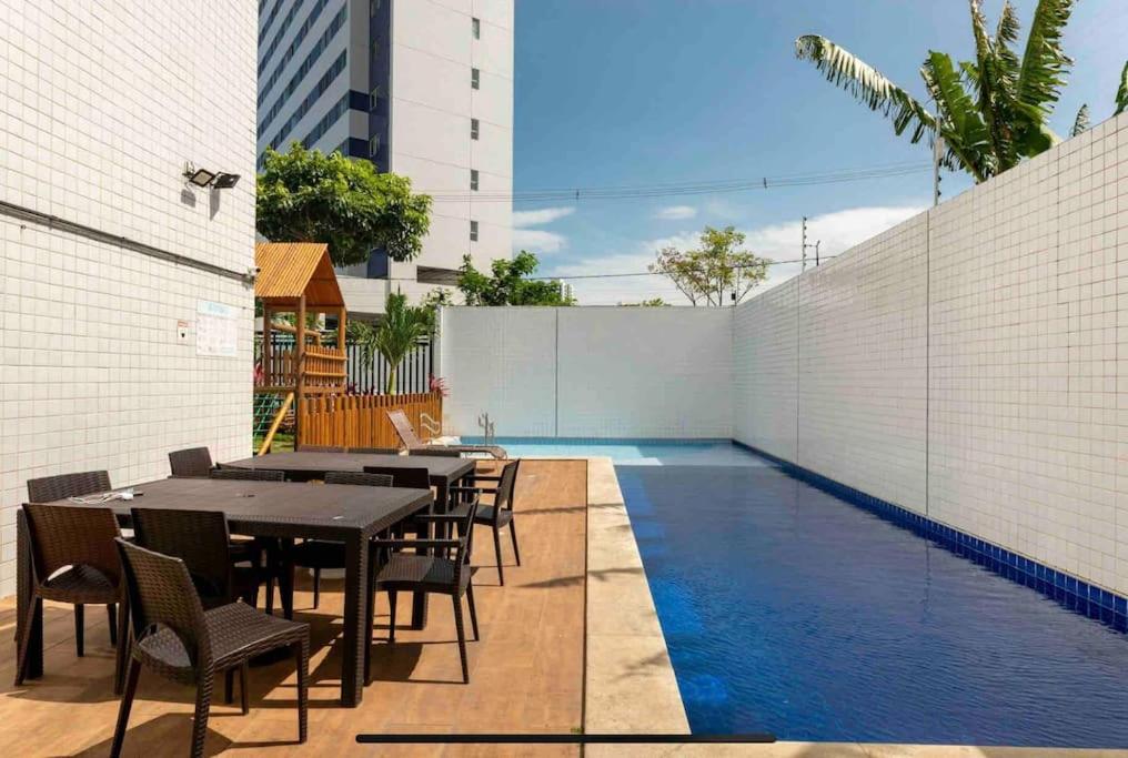 eine Terrasse mit Tischen und Stühlen neben einem Pool in der Unterkunft Coração de Boa Viagem in Recife