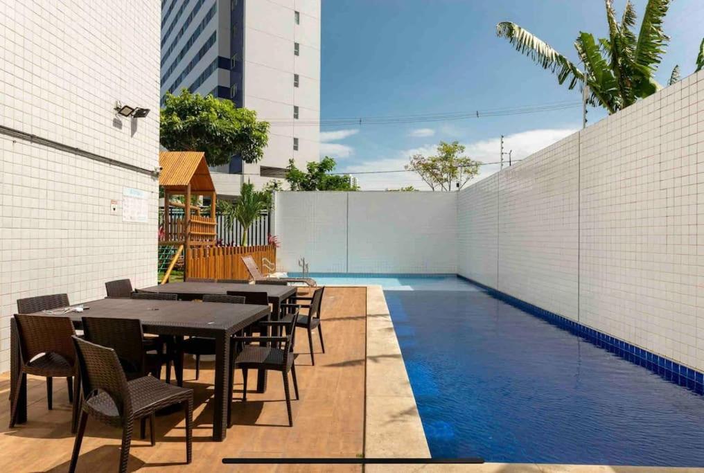 a patio with tables and chairs next to a swimming pool at Coração de Boa Viagem in Recife