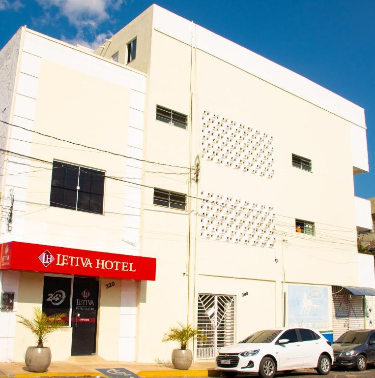 Un edificio blanco con un coche aparcado delante. en Hotel Letiva Centro, en Sobral