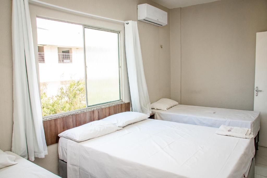 two beds in a room with a window at Letiva Hotel Centro in Sobral