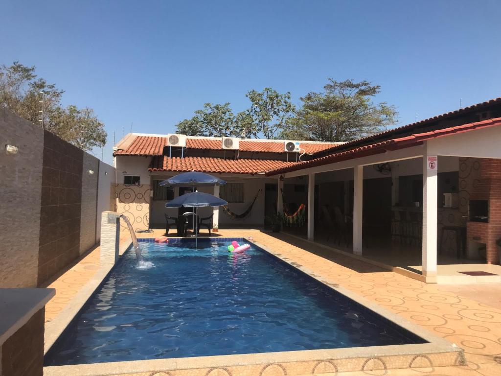 una piscina con sombrilla frente a una casa en Rancho peixe grande, en Sao Miguel do Araguaia