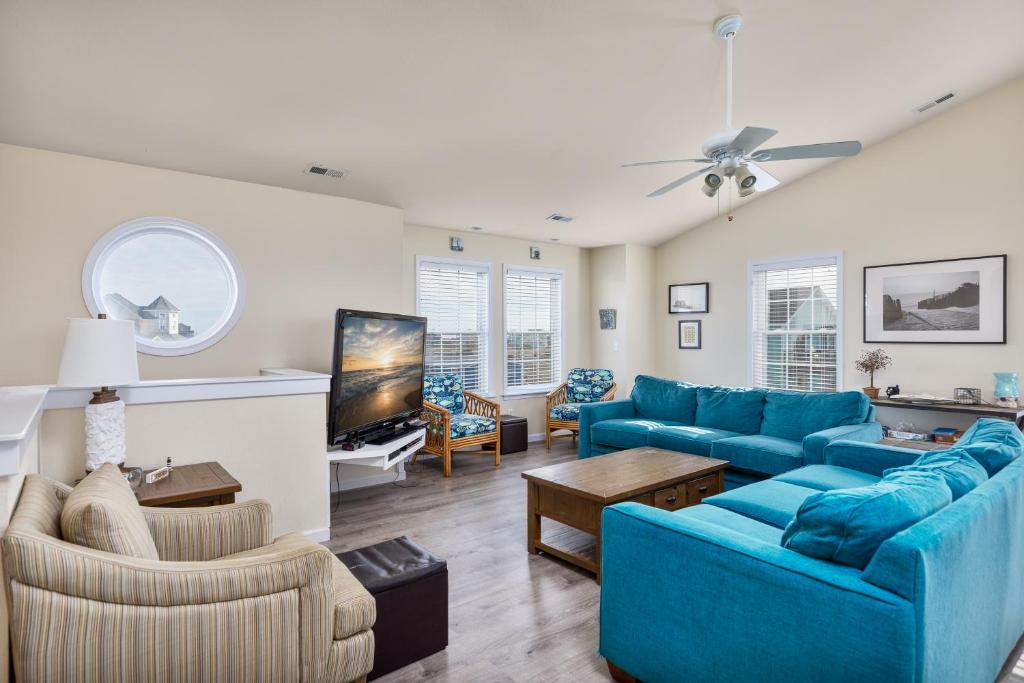 a living room with blue couches and a tv at 7030 - Waves Against the Machine by Resort Realty in Rodanthe