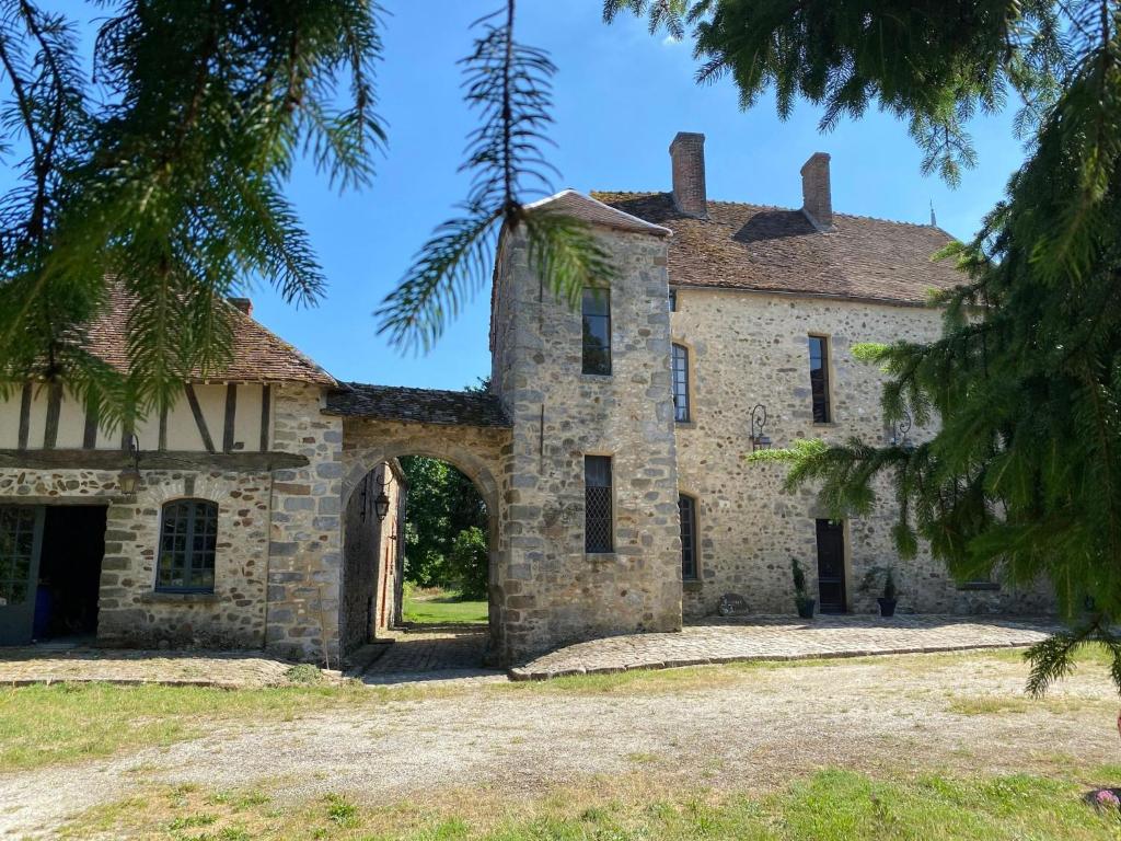 una antigua casa de piedra con un arco en LE SAINT LEONARD, en Montceaux-lès-Provins