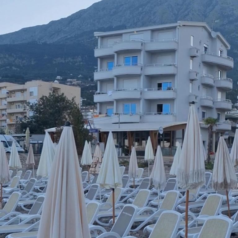 a bunch of white chairs and umbrellas in front of a building at Apartments Val in Dobra Voda