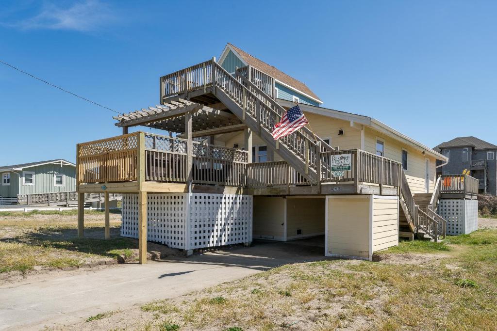 a house with a balcony with an american flag on it at 7039 - A Wave From It All by Resort Realty in Rodanthe