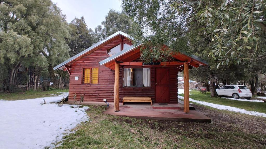 uma pequena cabana de madeira com um banco na relva em Cabañas Kuky em San Carlos de Bariloche