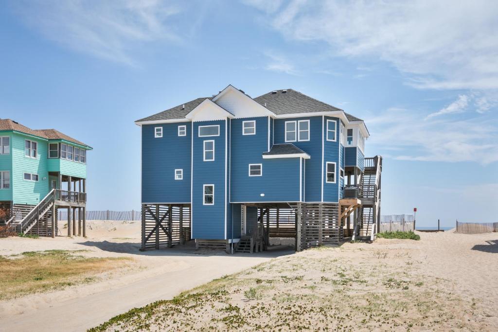 a blue house on the beach next to a building at 7048 - Tide Song by Resort Realty in Rodanthe
