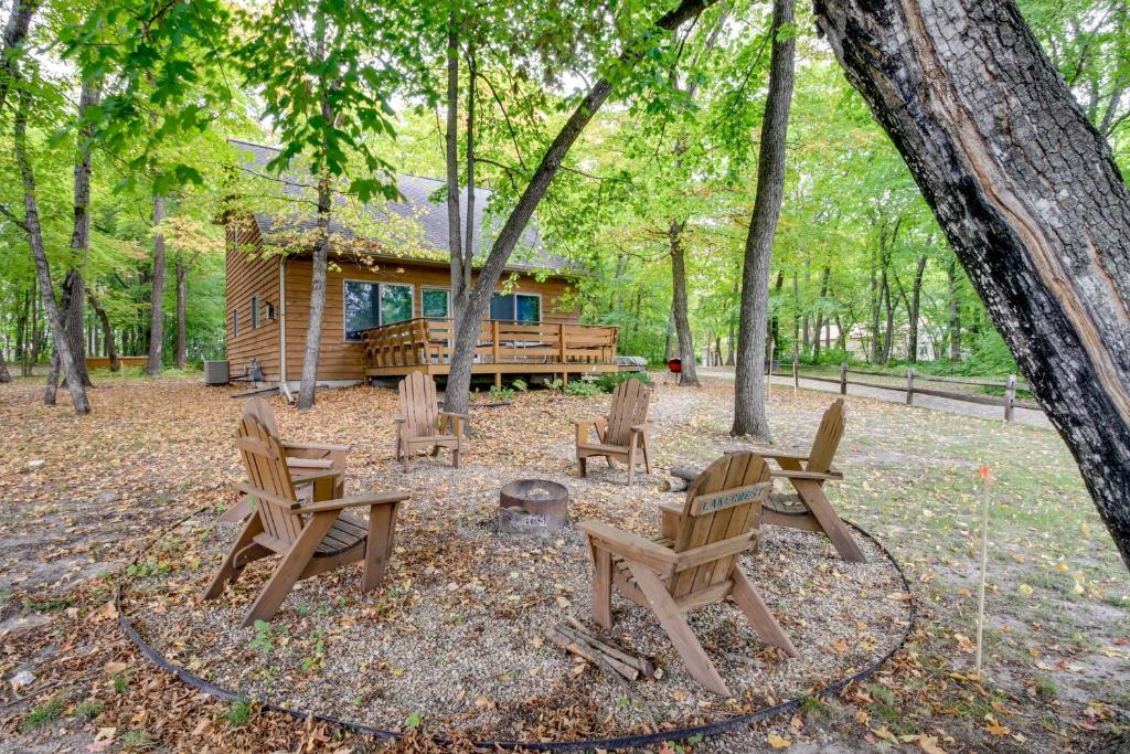eine Hütte im Wald mit Stühlen und einer Feuerstelle in der Unterkunft Detroit Lakes Cabin Rental on Long Lake! in Detroit Lakes