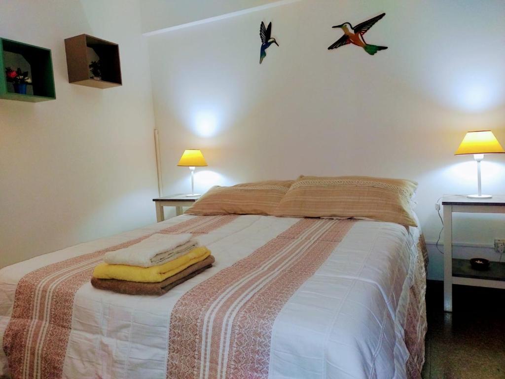a bedroom with a bed with two lamps and two towels at Departamento Mamá Lucia in Guaymallen