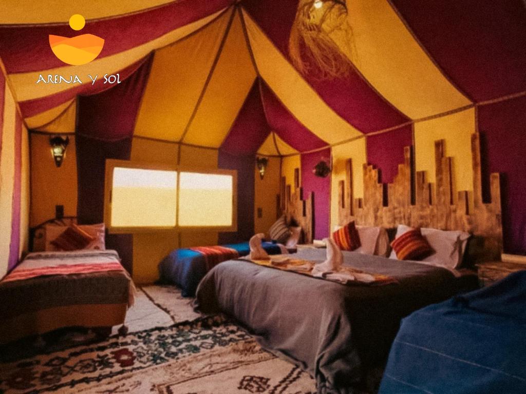 a room with two beds with people sitting on them at Arena y Sol Merzouga Camp in Merzouga