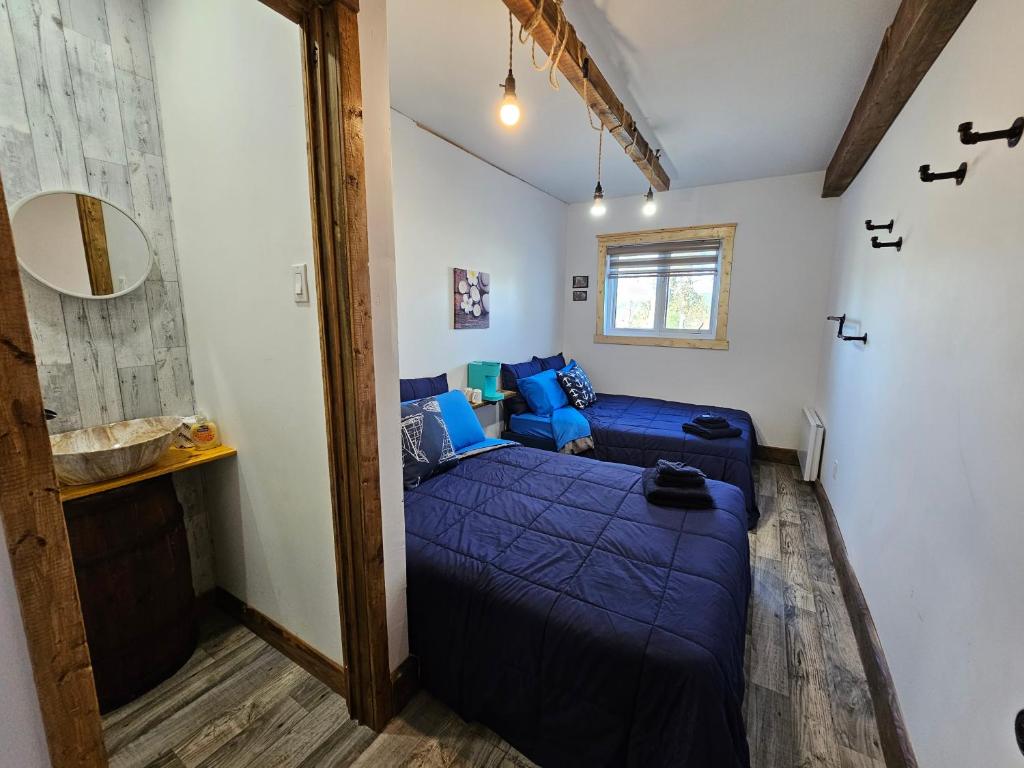 ein Schlafzimmer mit einem blauen Bett und einem Sofa in der Unterkunft Gite touristique eaux bons vievents in Lac-Bouchette
