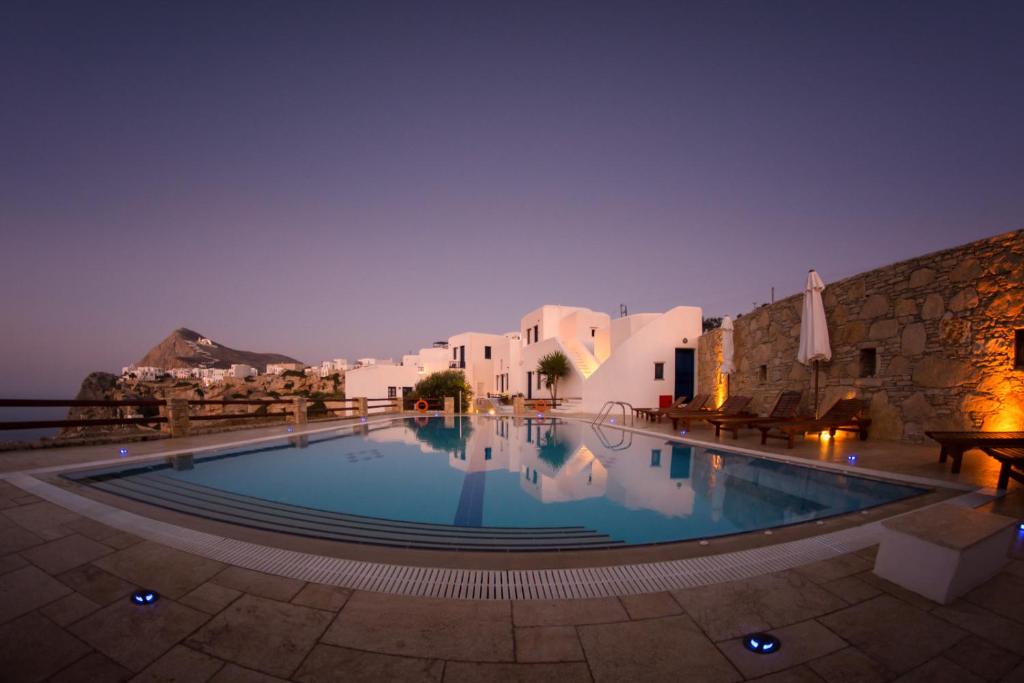 a large swimming pool in a courtyard with buildings at Anemousa Hotel in Chora Folegandros