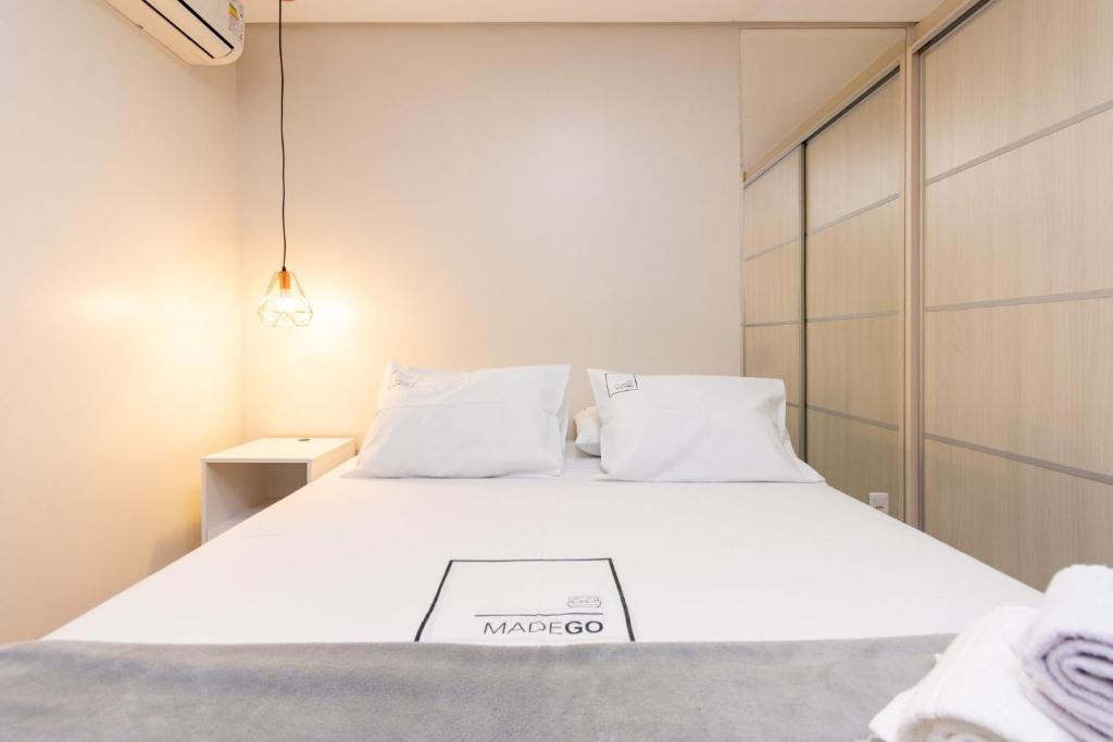 um quarto com uma cama grande e lençóis brancos em Conforto e Praticidade no Alto da Glória ESP2906 em Goiânia
