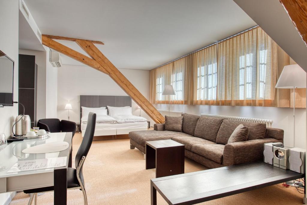 a living room with a couch and a bed at Hôtel Au Terminus in Sierre