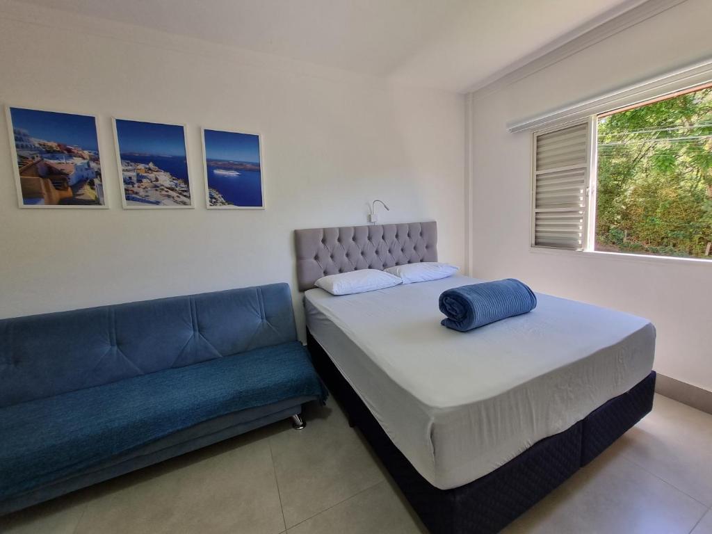 a bedroom with a bed and a couch at Apart Grécia l Aconchego nas Montanhas l Águas de Lindóia in Águas de Lindoia