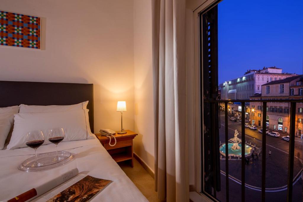 a bedroom with a bed with two glasses of wine at Suite Artis Barberini in Rome