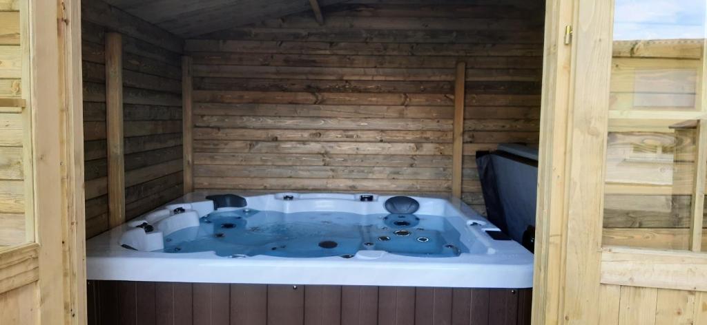 a jacuzzi tub in a wooden room at La Pinéguette maison 12 personnes décoration chalet/ sauna 4 personnes in La Bresse