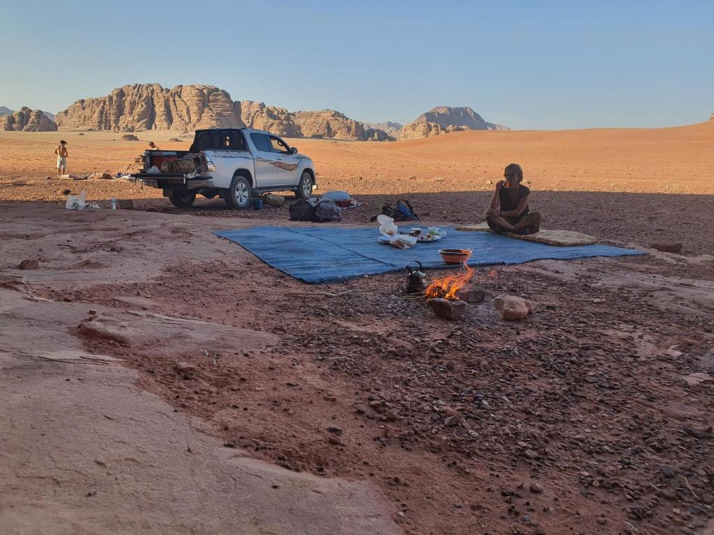 a woman sitting next to a fire in the desert at Bedouin Family Camp in Wadi Rum