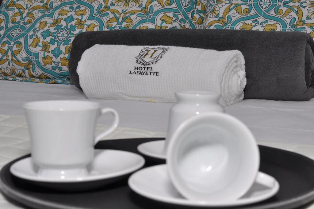 - un plateau avec 2 tasses et des soucoupes sur un lit dans l'établissement Hotel Lafayette, à Itaquaquecetuba