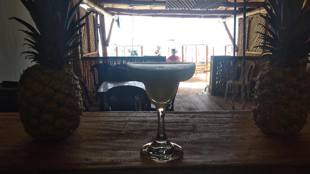 una copa de vino sentada en una mesa junto a dos piñas en Sol & Mar Perú Beach, en Playa Blanca