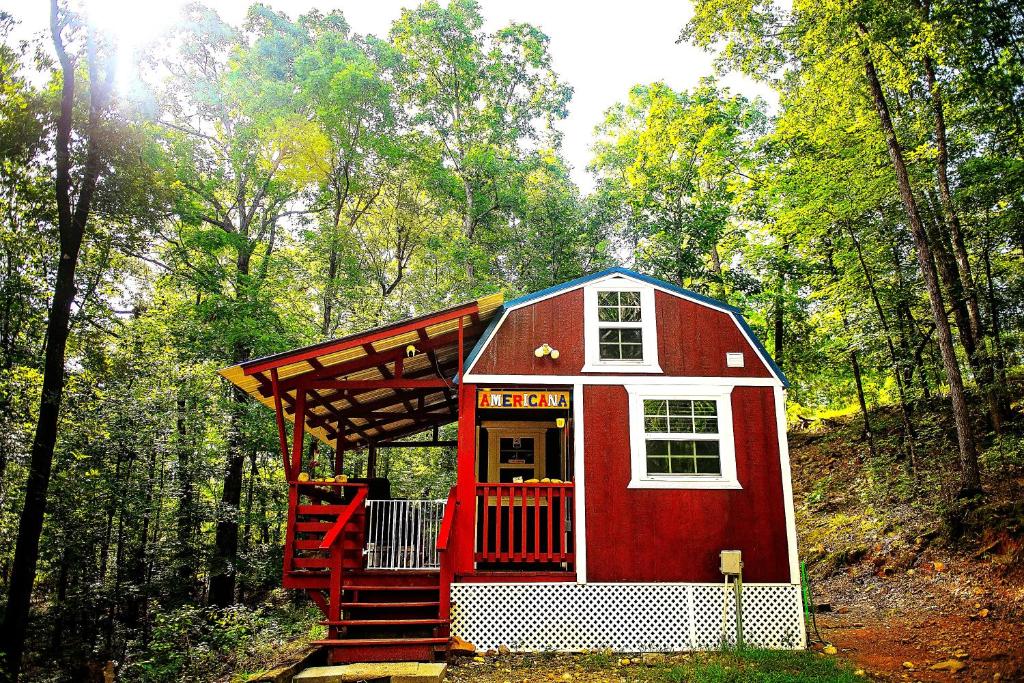 una casa roja y blanca en medio de un bosque en The Americana - Parker Creek Bend Cabins en Murfreesboro