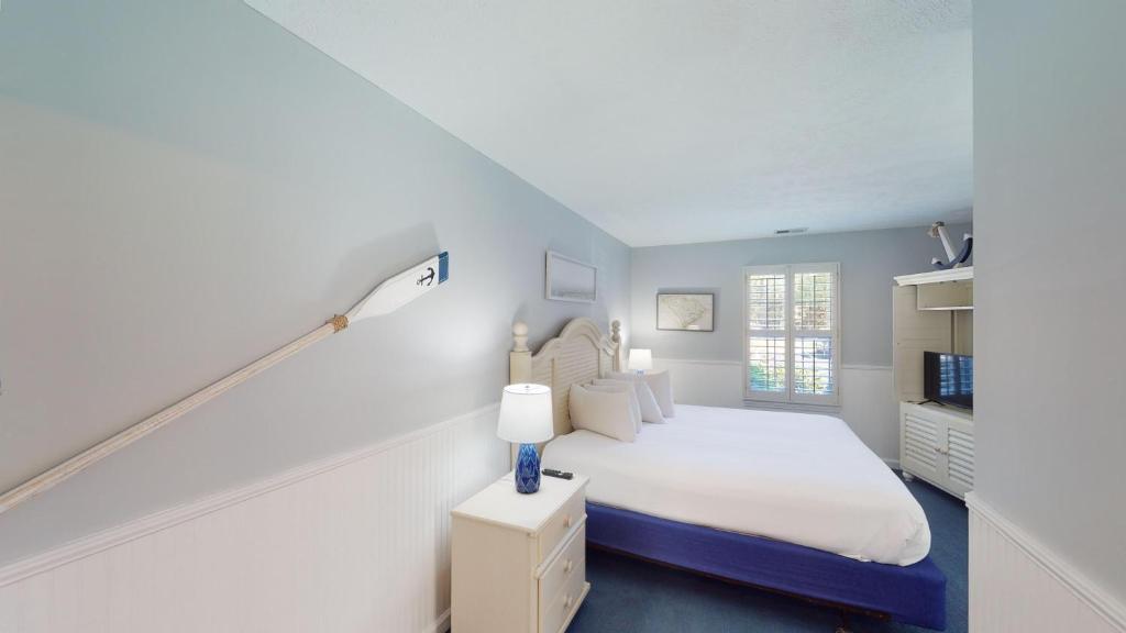 a white bedroom with a bed and a lamp at True Blue Villas Your 3BR Oasis in Pawleys Island