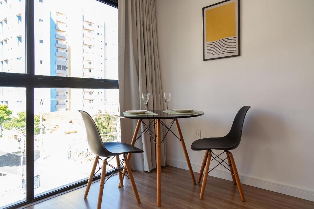 a dining room with a table and chairs and a window at Maravilhoso e elegante studio para casal PGO412 in Poços de Caldas