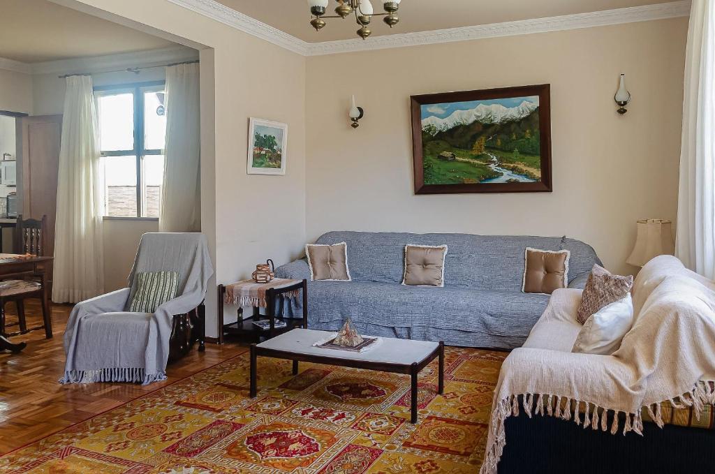 Chamosa e aconchegante casa em Petrópolis VGL041 في بتروبوليس: غرفة معيشة مع أريكة زرقاء وطاولة