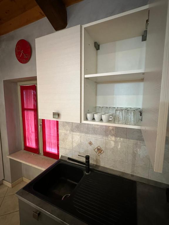 a kitchen with a sink and a red window at La tana di Piozzo in Piozzo