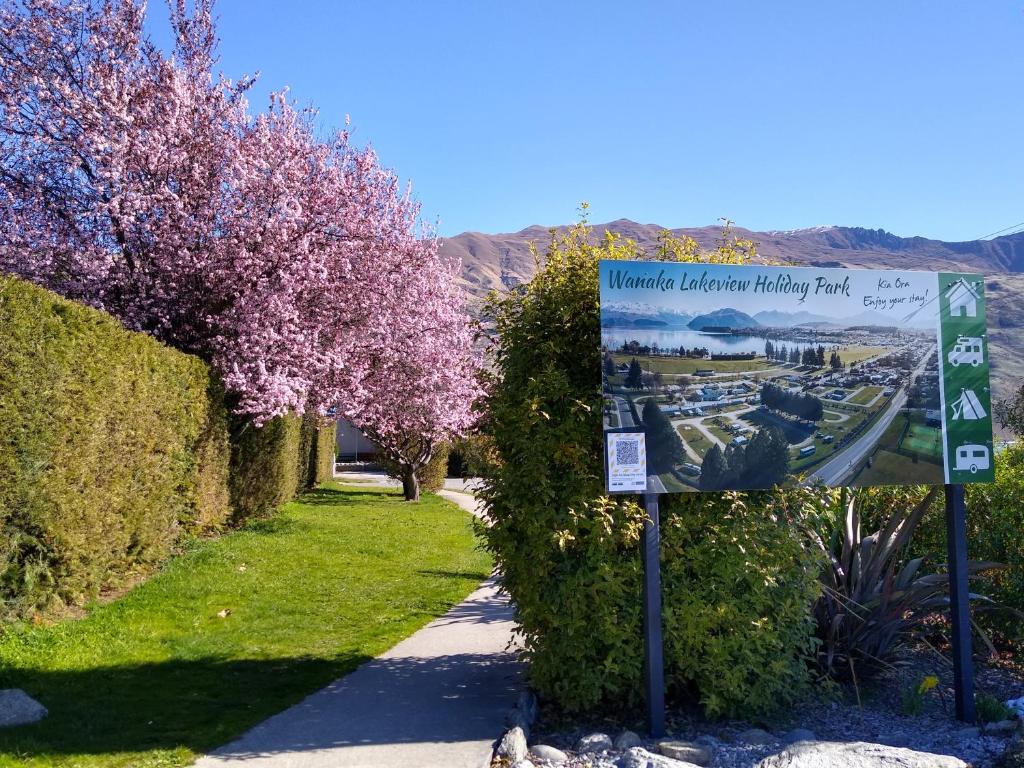 a sign on a sidewalk next to a garden at Hampshire Holiday Parks - Wanaka in Wanaka