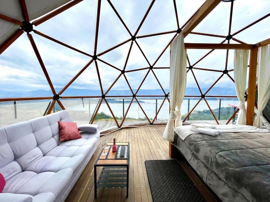 Habitación con sofá blanco y techo de cristal. en Lujoso Glamping MarQua Spa Guatavita Wifi Cocina, en Guatavita