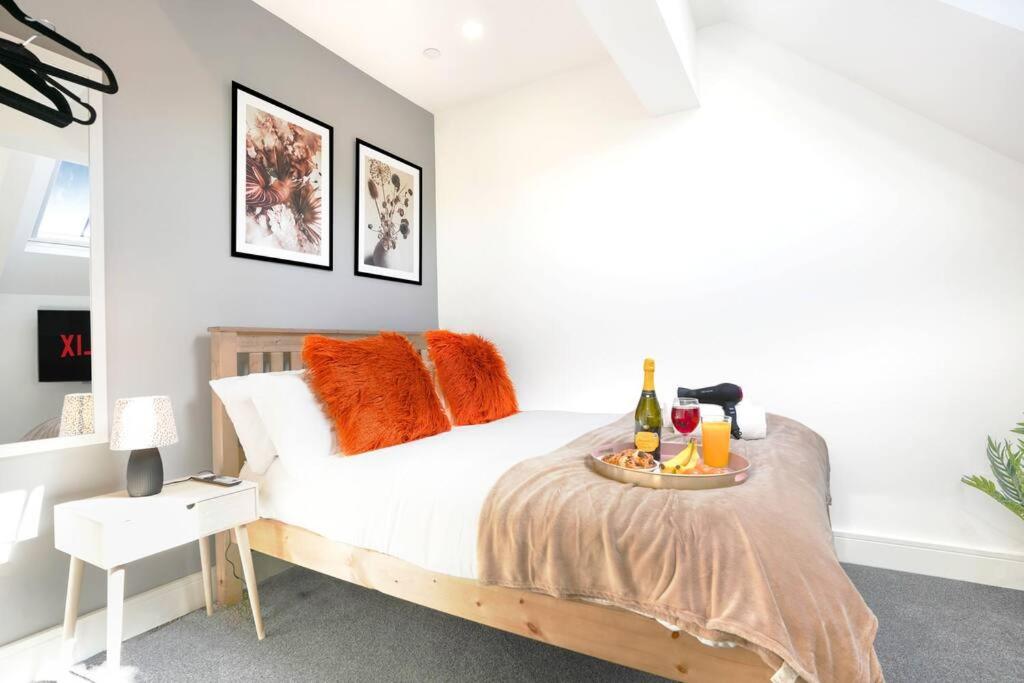 een slaapkamer met een bed met oranje kussens en een dienblad met drankjes erop. bij Central Buckingham Apartment #3 with Free Parking, Pool Table, Fast Wifi and Smart TV with Netflix by Yoko Property in Buckingham