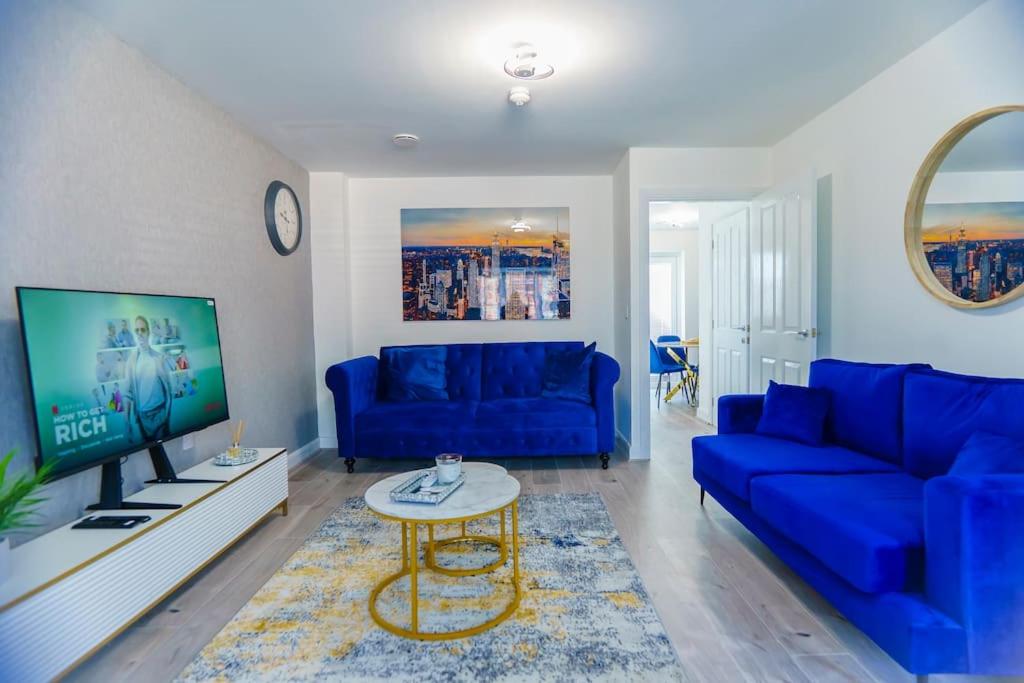 ein Wohnzimmer mit blauen Sofas und einem TV in der Unterkunft Caasi Homes in Leigh