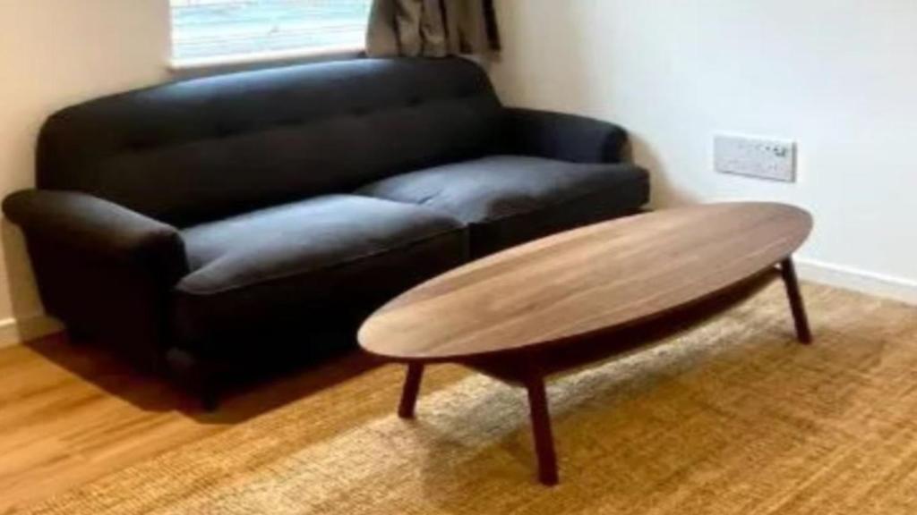 a black couch and a wooden coffee table in a living room at Chalet Gentianes Isere in Val-d'Isère