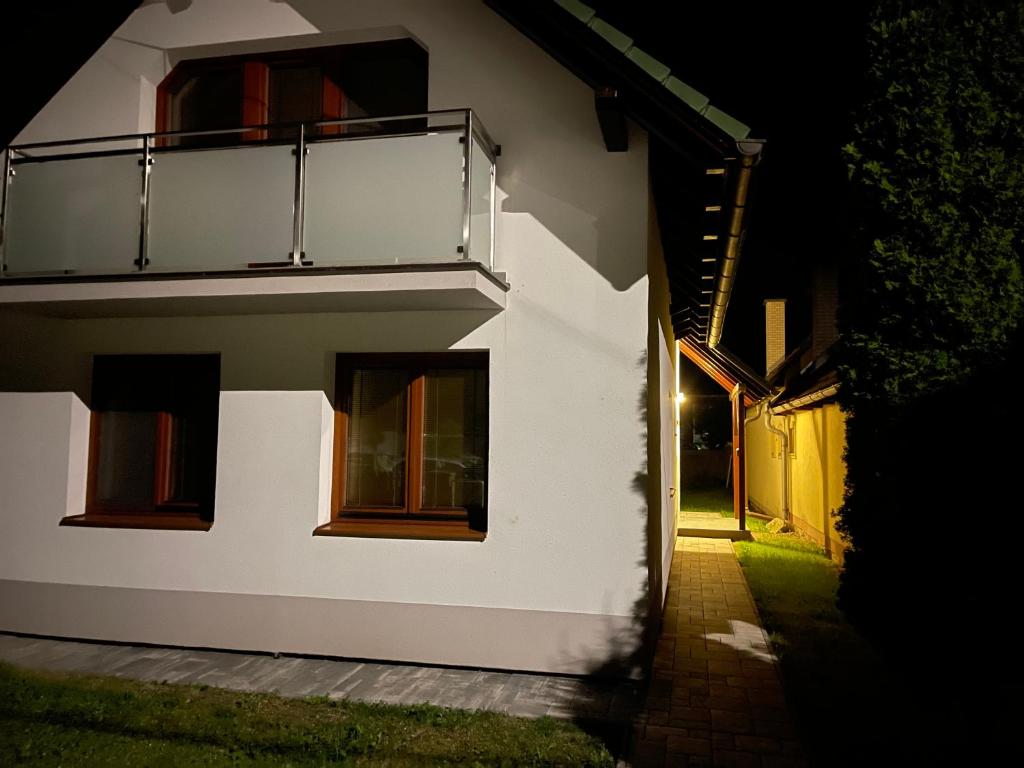 a white house with a balcony at night at Dom Príbovce in Príbovce