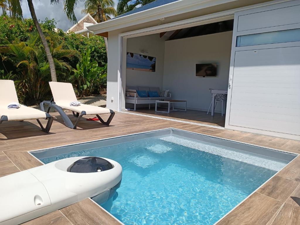 a swimming pool with two chairs and a table at Soley Bungalows Nonis 2 pers Adult only in Sainte-Anne