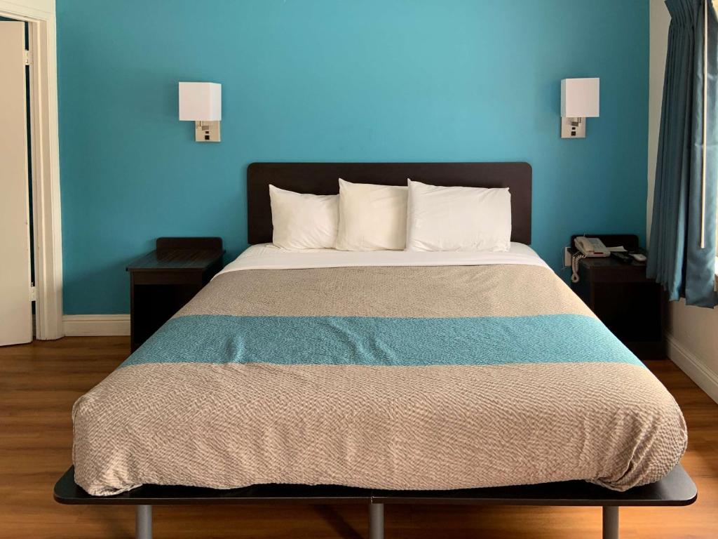 een slaapkamer met een bed met een blauwe muur bij Motel 6 Pismo Beach CA Pacific Ocean in Pismo Beach