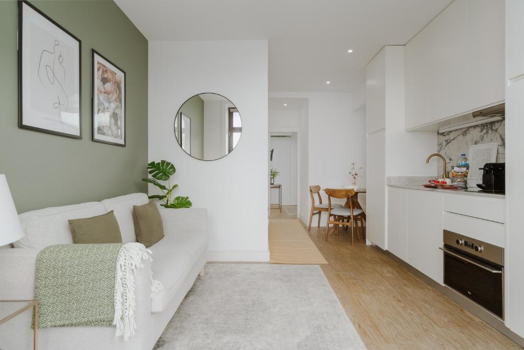 een woonkamer met een witte bank en een spiegel bij Downtown Terrace Flat with AC and Patio - feel like a local in Porto