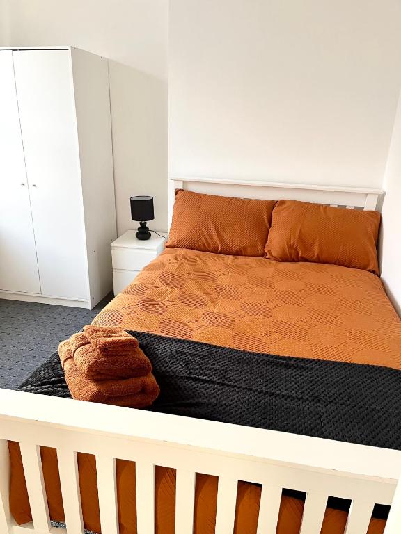 ein Schlafzimmer mit einem großen Bett mit einer orangefarbenen Bettdecke in der Unterkunft Convenient & Modern Private Bedroom Space near Barnsley Hospital in Barnsley