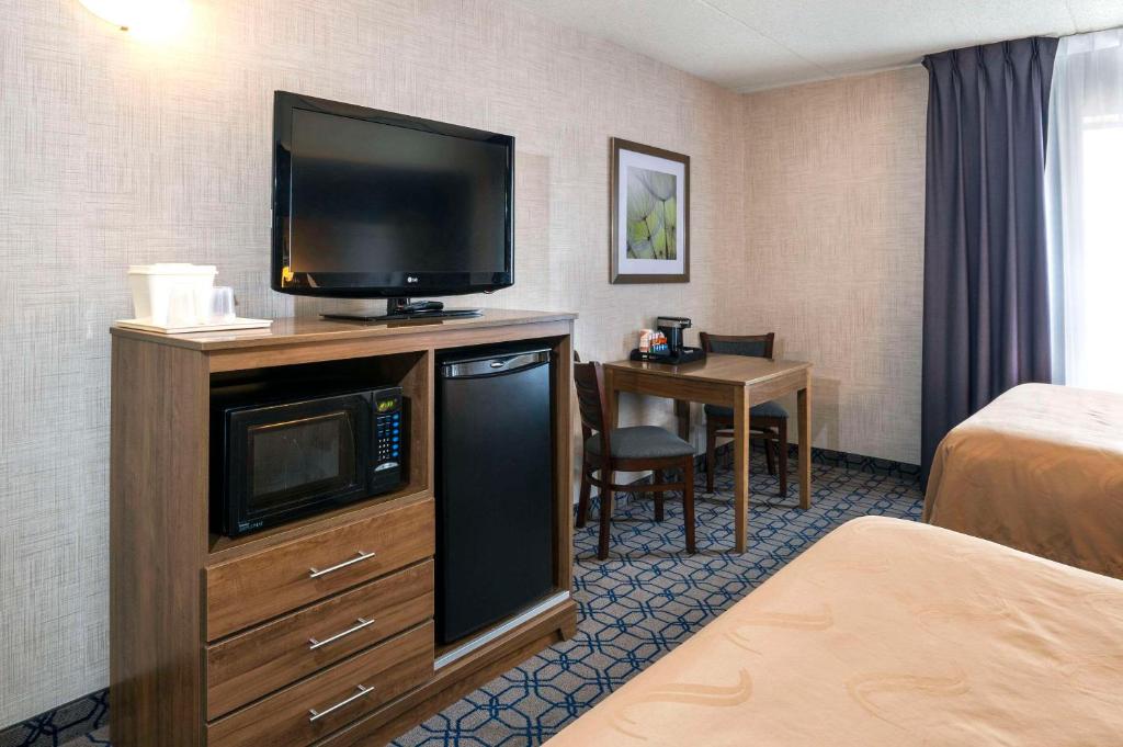 a hotel room with a flat screen tv on a dresser at Quality Suites in Whitby