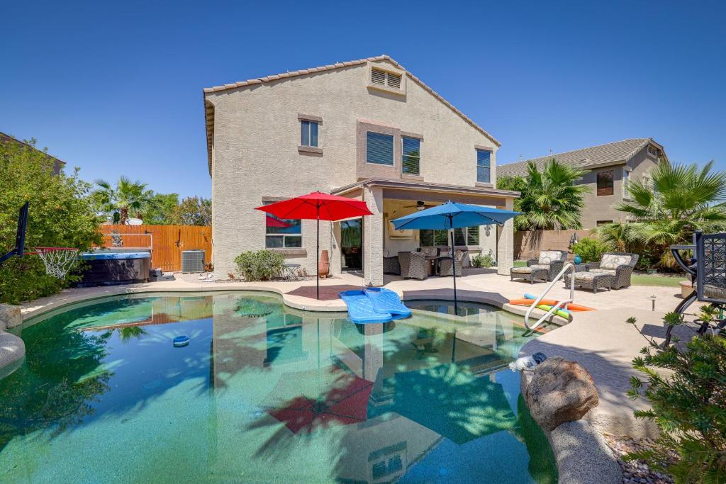 a swimming pool with two umbrellas and a house at Spacious Maricopa Home Rental with Pool and Hot Tub! in Maricopa