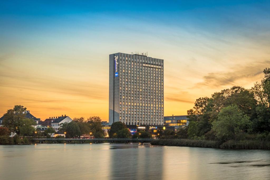 a tall building sitting next to a river at sunset at Radisson Blu Scandinavia Hotel, Copenhagen in Copenhagen