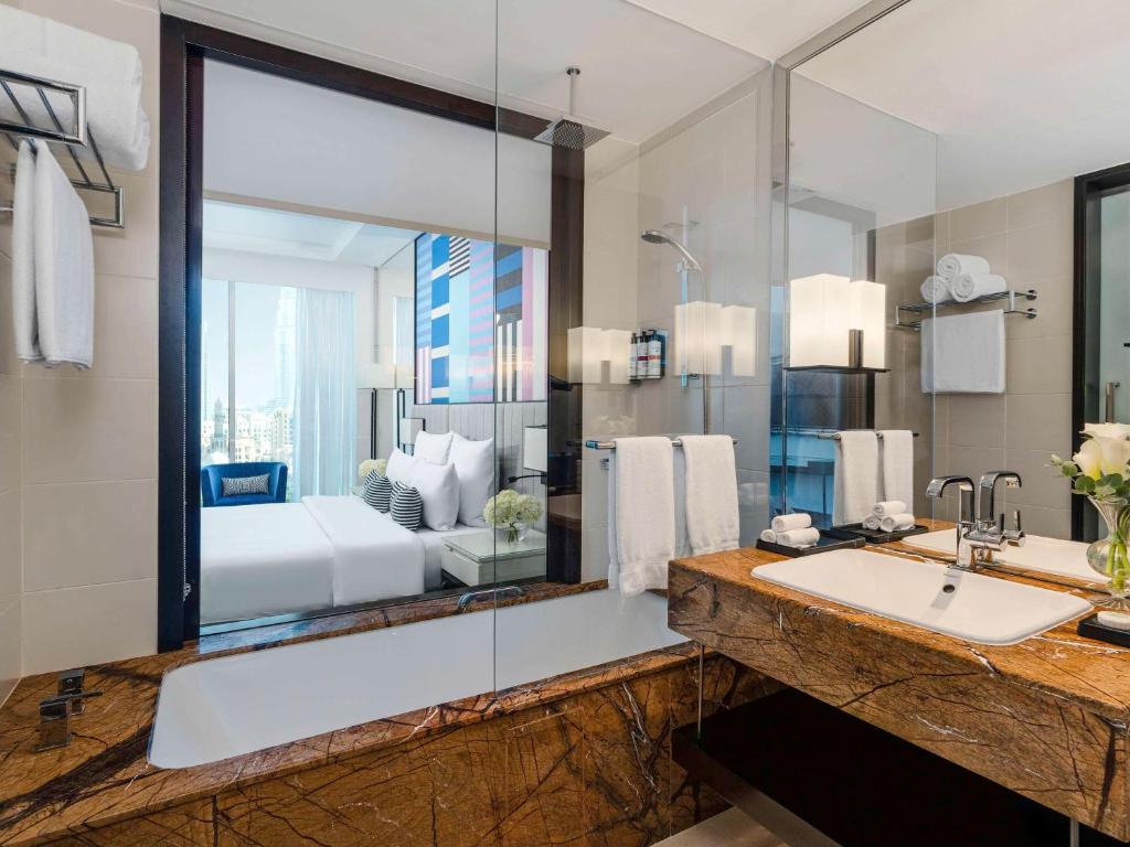 uma casa de banho com um lavatório e um espelho grande em Pullman Dubai Downtown em Dubai