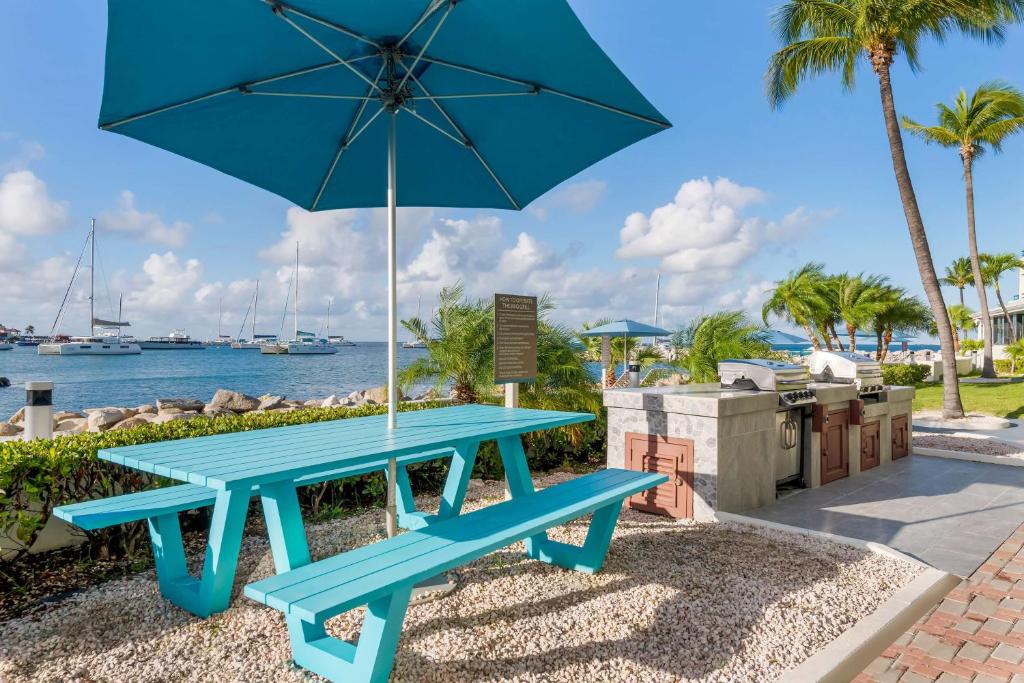 a blue picnic table with an umbrella next to the water at Hilton Vacation Club Royal Palm St Maarten in Simpson Bay