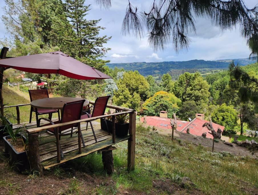 una mesa y sillas sentadas en un banco con sombrilla en Un paraíso en la montaña Bogotá Verjon Via La Calera en Bogotá