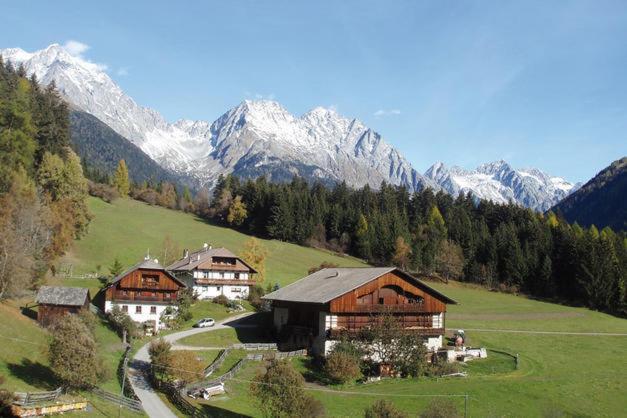 un grupo de casas en una colina con montañas cubiertas de nieve en Wiesemann Biohof, en Anterselva di Mezzo