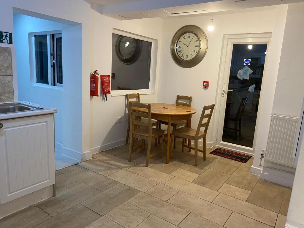 eine Küche mit einem Tisch und Stühlen sowie einer Uhr an der Wand in der Unterkunft Calm house twin beds in Wyken