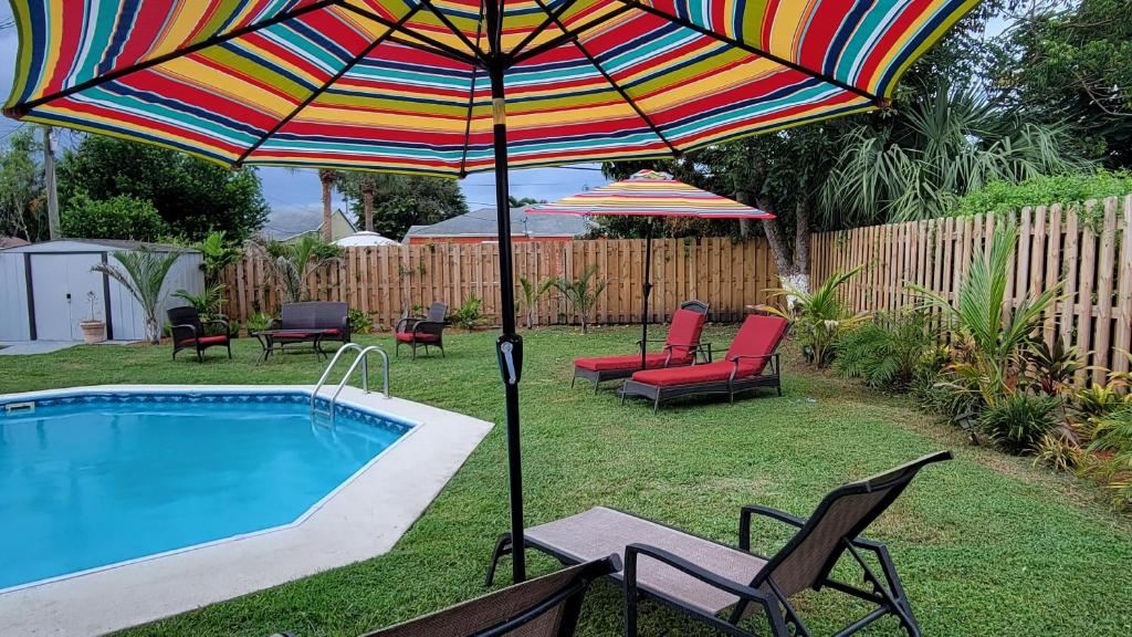 a colorful umbrella and chairs next to a swimming pool at West Palm Beach Tropical Oasis in West Palm Beach
